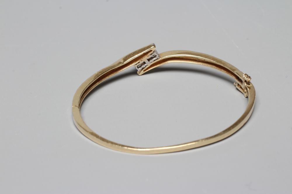 A DIAMOND STIFF HINGED BANGLE, the upper section with three brilliant cut stones in an open Image