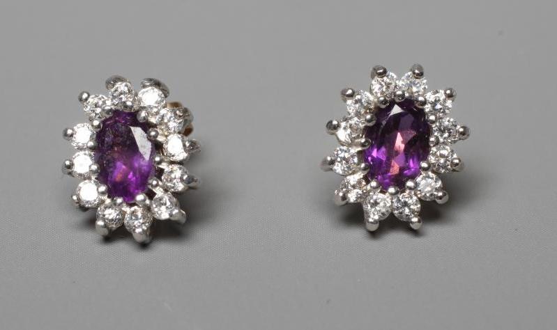 A PAIR OF AMETHYST AND DIAMOND CLUSTER EAR STUDS, the oval facet cut amethysts claw set to a border Image