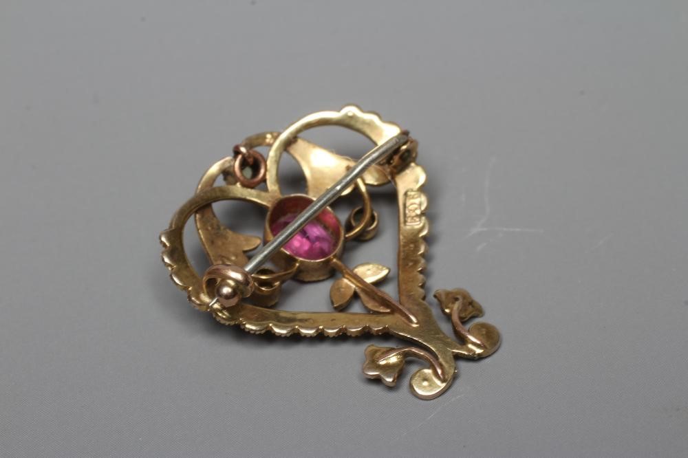 AN EDWARDIAN BROOCH/PENDANT, the open heart panel set with seed pearls and centred by an oval facet Image