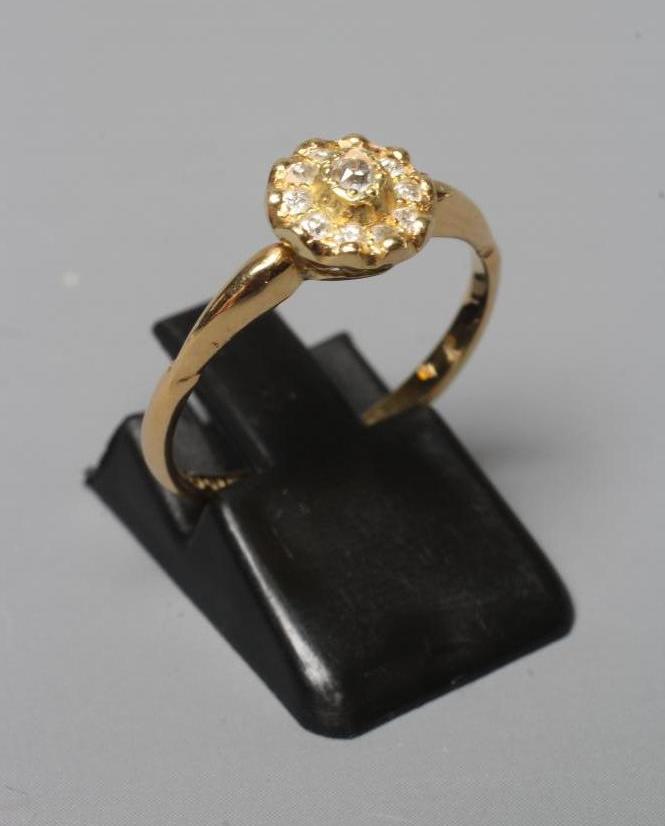 AN EDWARDIAN DIAMOND CLUSTER RING, the ten mix cut stones in rub over setting to a plain 18ct gold Image