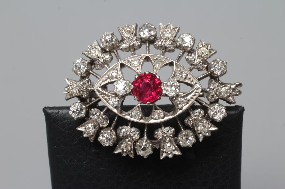 A RUBY AND DIAMOND BROOCH, the central circular facet cut ruby claw set to open borders of old mix Image