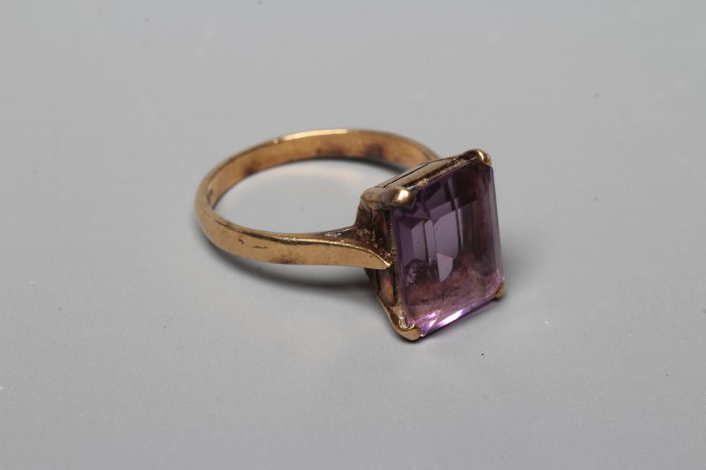 AN AMETHYST DRESS RING, the oblong facet cut stone claw set to a plain 9ct gold shank, Birmingham Image