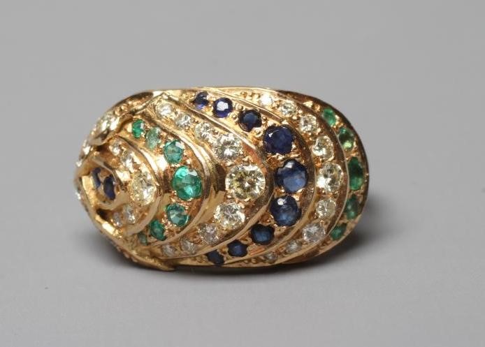 A MULTI-GEM COCKTAIL RING, the oval panelled boss set with rows of diamonds, emeralds and sapphires Image
