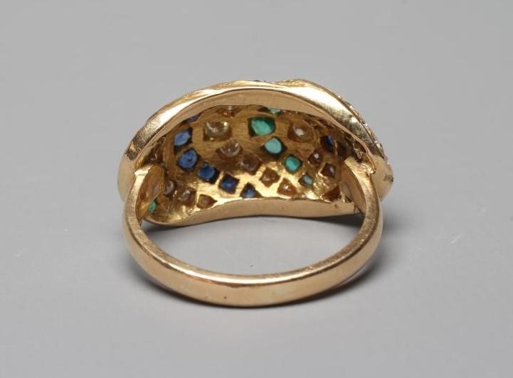 A MULTI-GEM COCKTAIL RING, the oval panelled boss set with rows of diamonds, emeralds and sapphires Image