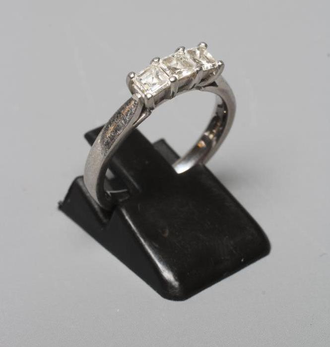 A THREE STONE DIAMOND RING, the Princess cut stones point set to a plain platinum shank, sponsor Image