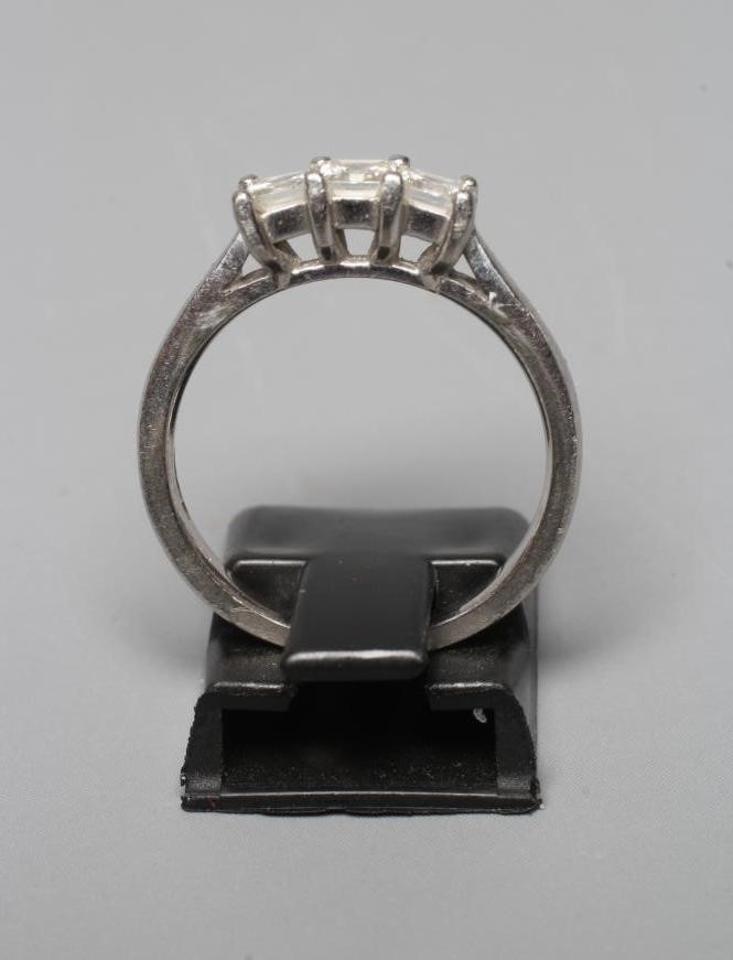 A THREE STONE DIAMOND RING, the Princess cut stones point set to a plain platinum shank, sponsor Image
