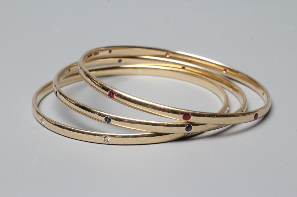 A MATCHED SET OF THREE STONE SET 9CT GOLD BANGLES Image