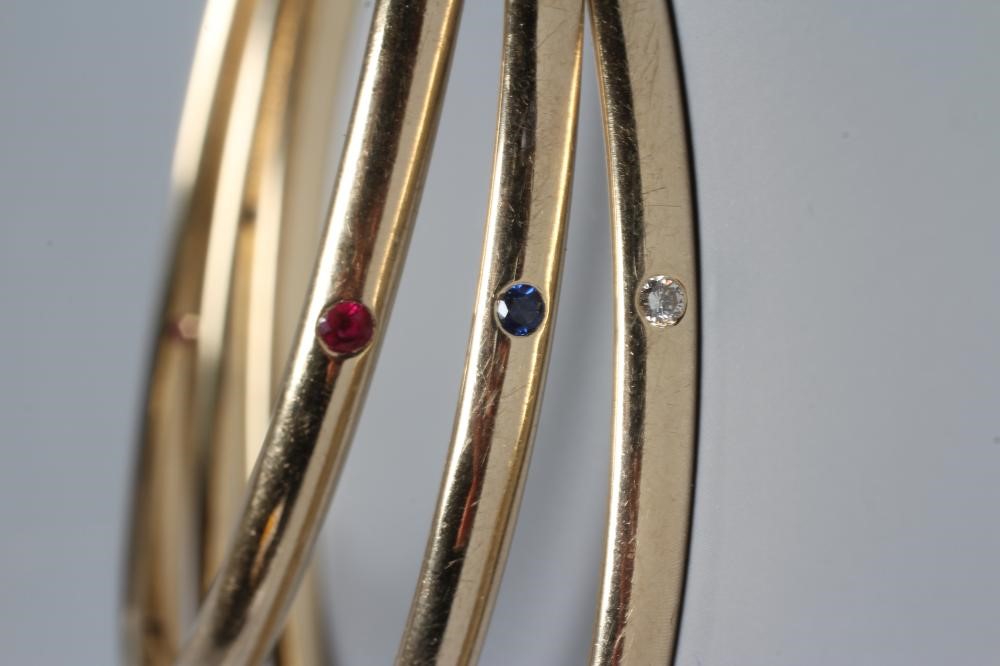 A MATCHED SET OF THREE STONE SET 9CT GOLD BANGLES Image