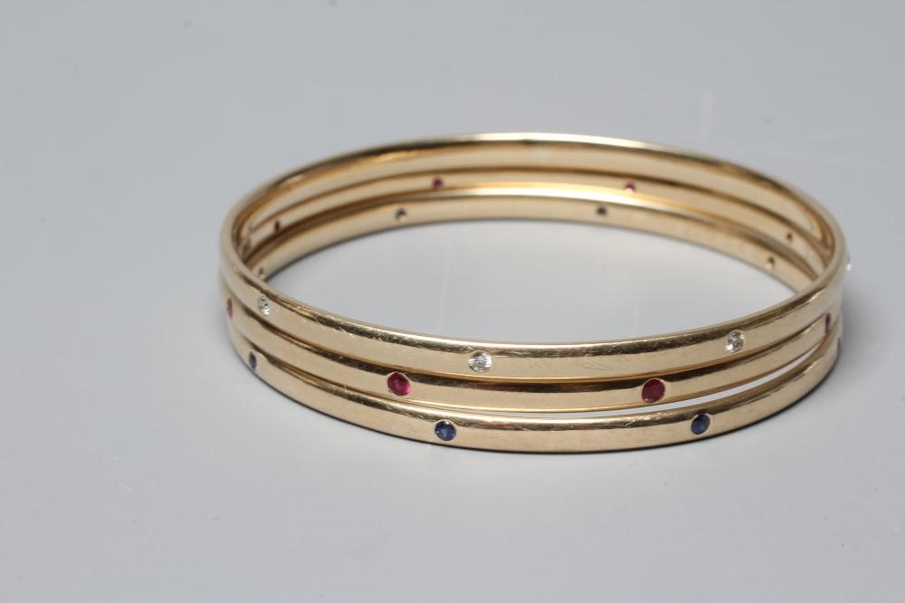 A MATCHED SET OF THREE STONE SET 9CT GOLD BANGLES Image