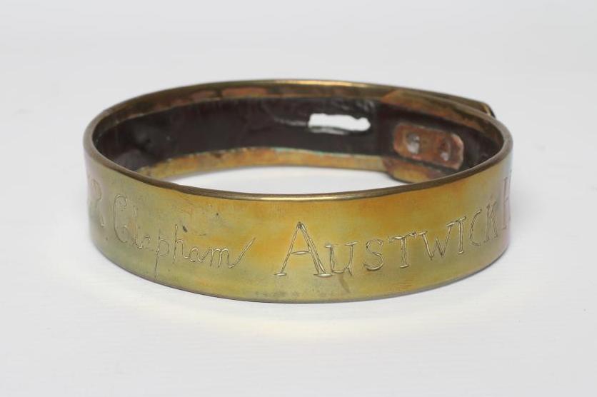 A BRASS DOG COLLAR, early 19th century, engraved 'T R Clapham, Austwick Hall', leather lined, 4 1/2" Image