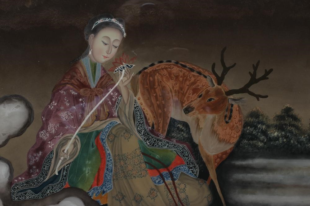 A CHINESE REVERSE PAINTING ON GLASS of a young lady in landscape holding a flower with a deer beside Image