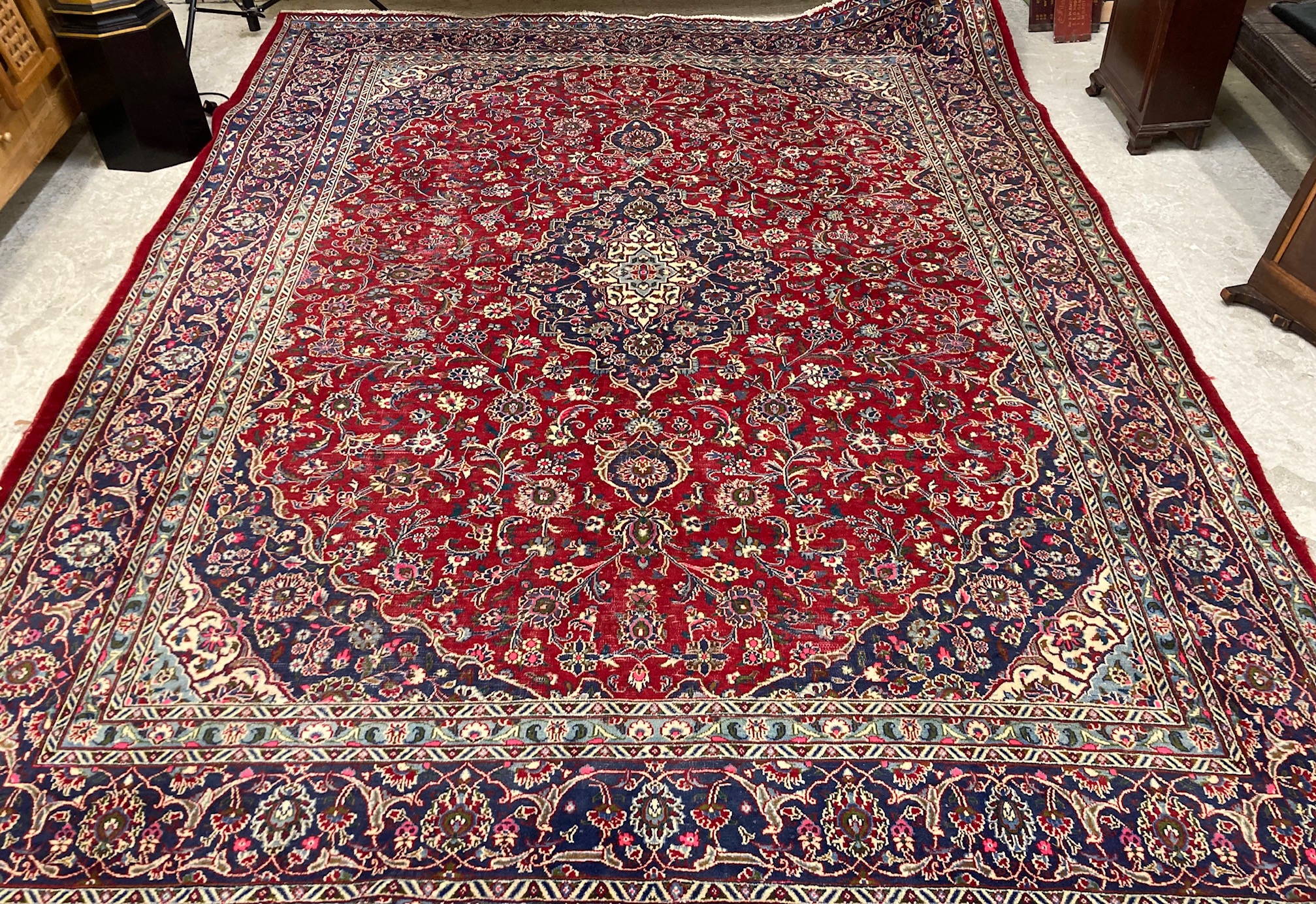 A KASHAN RUG, with central floral medallion on a red ground surrounded by light and dark blue floral Image