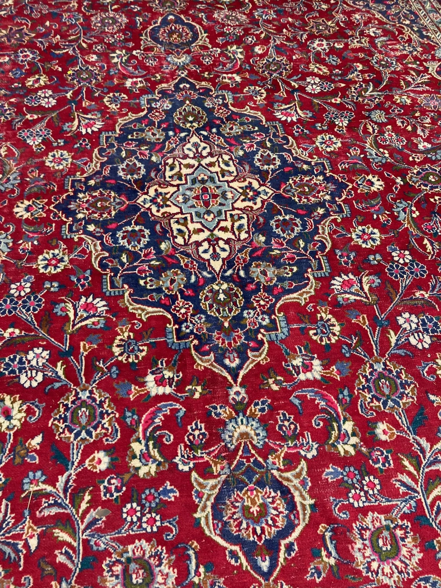 A KASHAN RUG, with central floral medallion on a red ground surrounded by light and dark blue floral Image