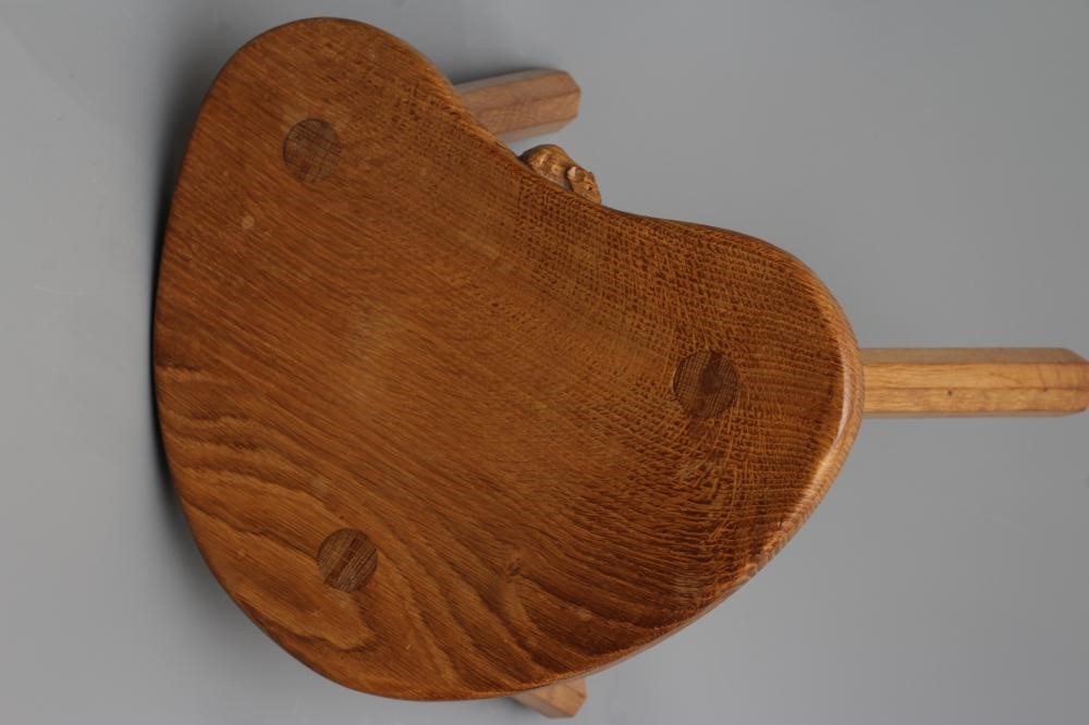 A ROBERT THOMPSON ADZED OAK COW STOOL, the dished kidney shaped top raised on three faceted splayed Image