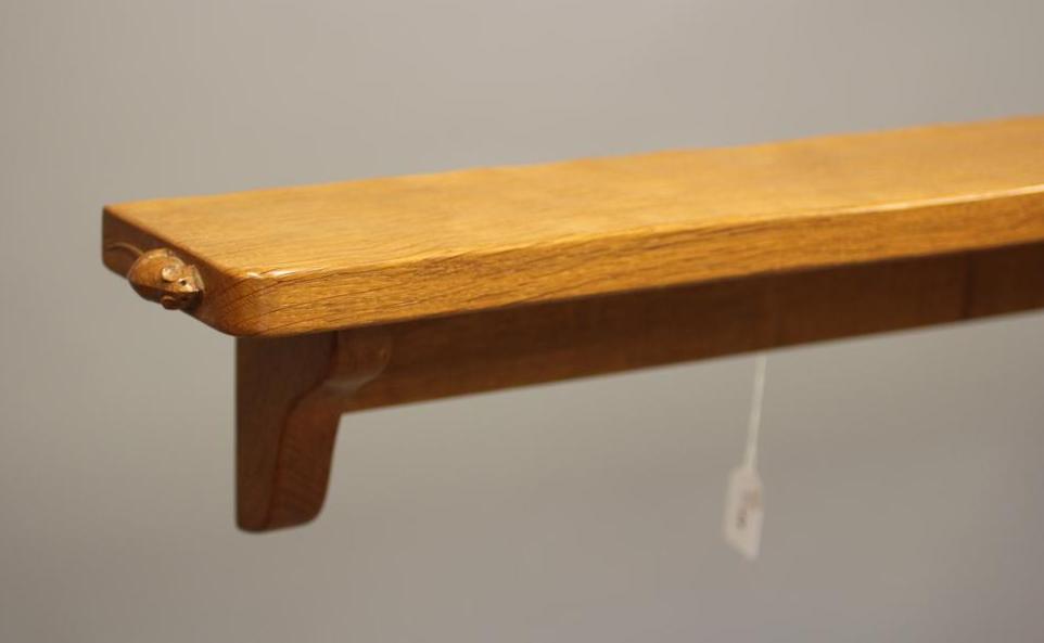 A ROBERT THOMPSON ADZED OAK WALL SHELF of rounded oblong form on ogee end brackets Image