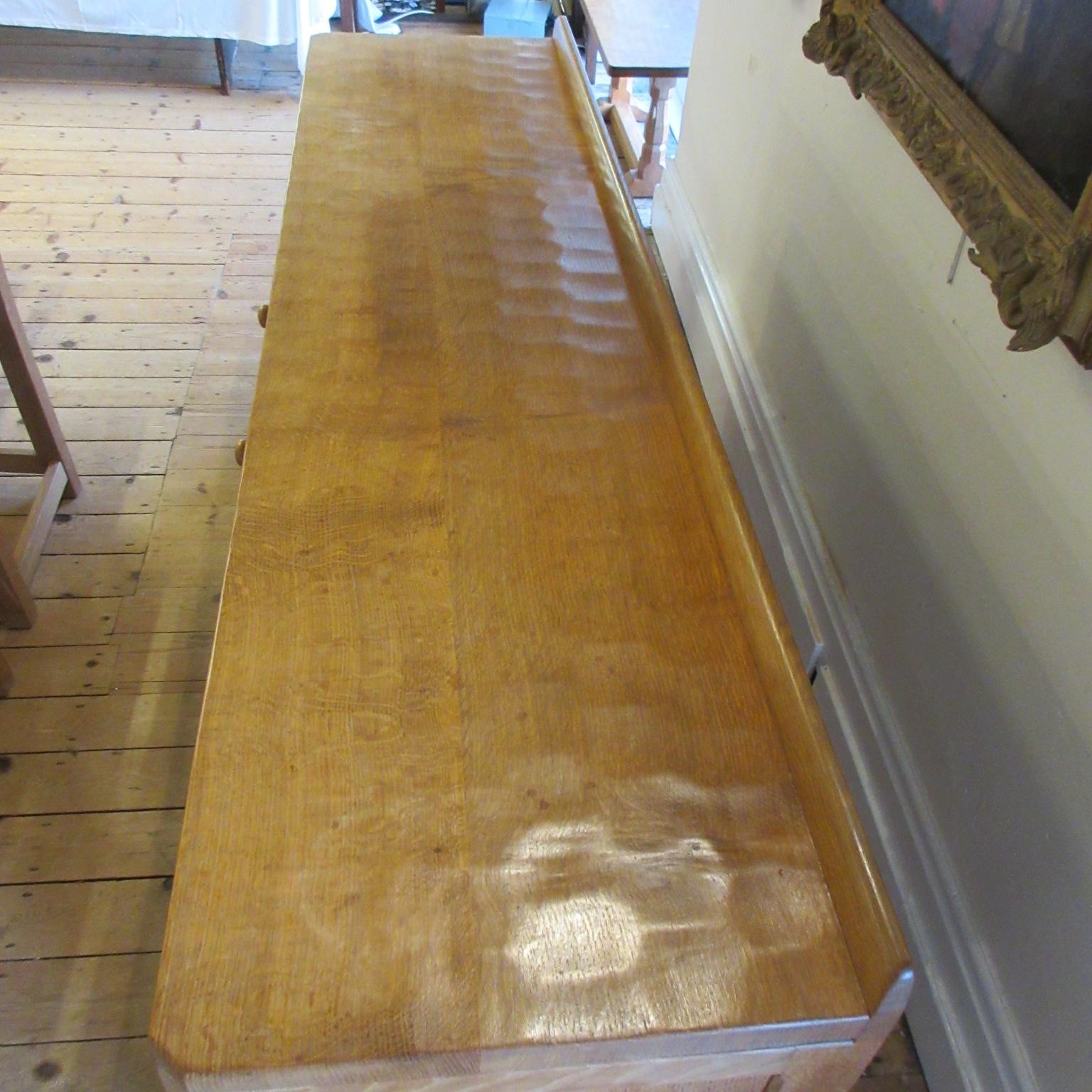 A ROBERT THOMPSON ADZED OAK SIDEBOARD of canted oblong form with ledge back Image