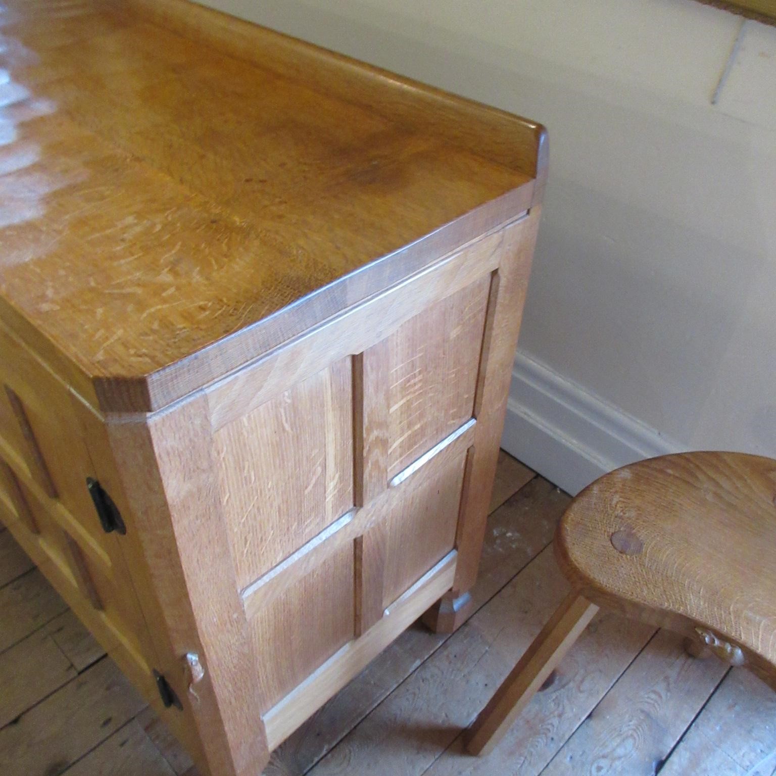 A ROBERT THOMPSON ADZED OAK SIDEBOARD of canted oblong form with ledge back Image