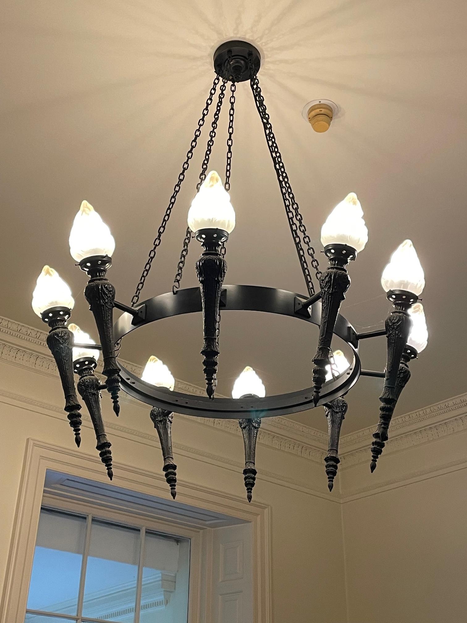 AN EBONISED METAL TEN LIGHT CEILING PENDANT, 20th century, the circlet suspended from chains and Image