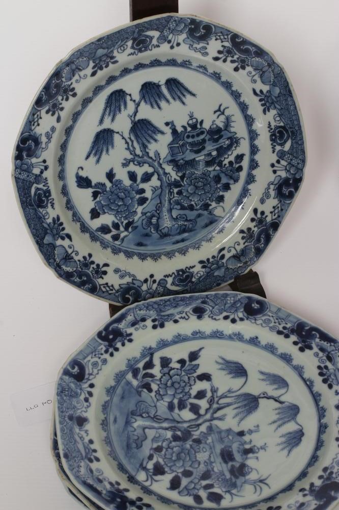 A SET OF SIXTEEN CHINESE PORCELAIN OCTAGONAL PLATES painted in underglaze blue with vases on a table Image