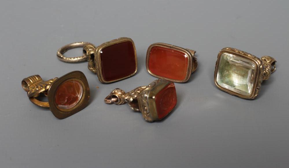 FIVE GEORGIAN AND LATER GILT METAL FOB SEALS, four set with cornelian (one engraved with a lion Image