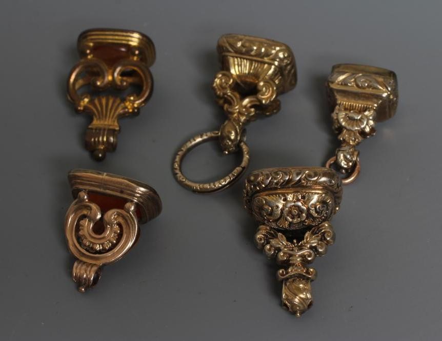 FIVE GEORGIAN AND LATER GILT METAL FOB SEALS, four set with cornelian (one engraved with a lion Image