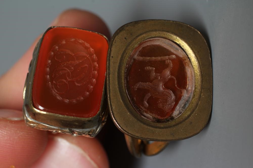 FIVE GEORGIAN AND LATER GILT METAL FOB SEALS, four set with cornelian (one engraved with a lion Image