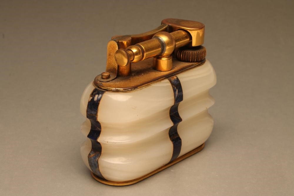A DUNHILL WHITE ONYX TABLE LIGHTER of ribbed oblong form inset with lapis lazuli angles Image