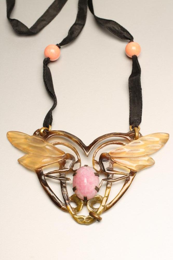 A GYP PRESSED AND STAINED HORN PENDANT modelled as a pair of dragonflies centred by an oval mottled Image