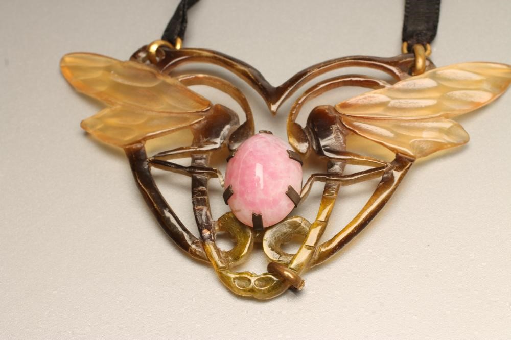 A GYP PRESSED AND STAINED HORN PENDANT modelled as a pair of dragonflies centred by an oval mottled Image