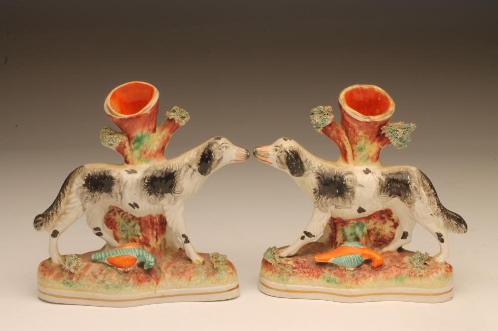 A PAIR OF VICTORIAN STAFFORDSHIRE POTTERY SPILL VASES as black and white retrievers standing against Image