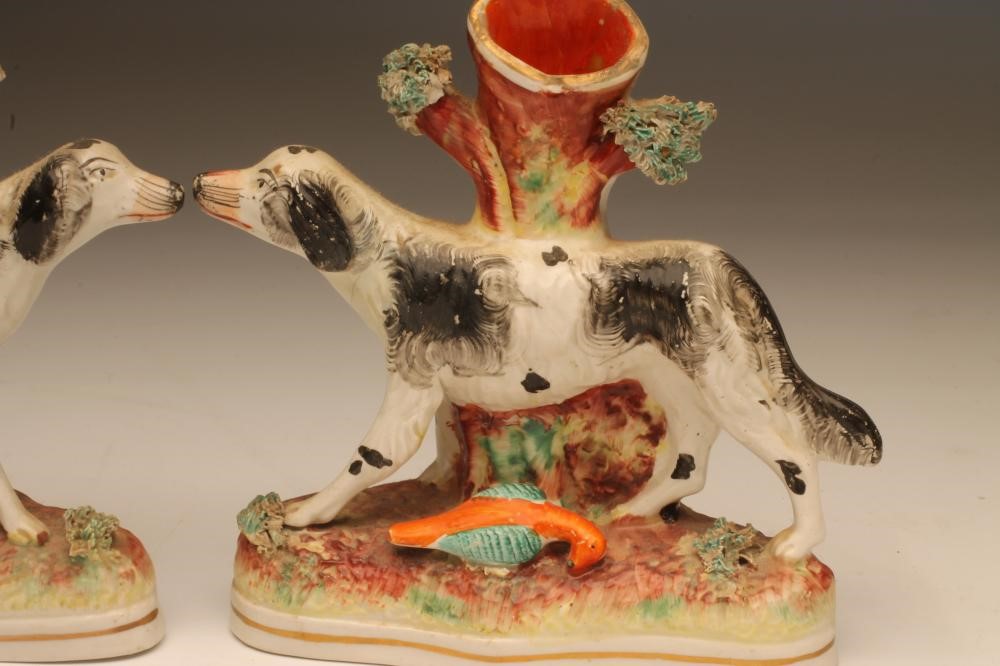 A PAIR OF VICTORIAN STAFFORDSHIRE POTTERY SPILL VASES as black and white retrievers standing against Image