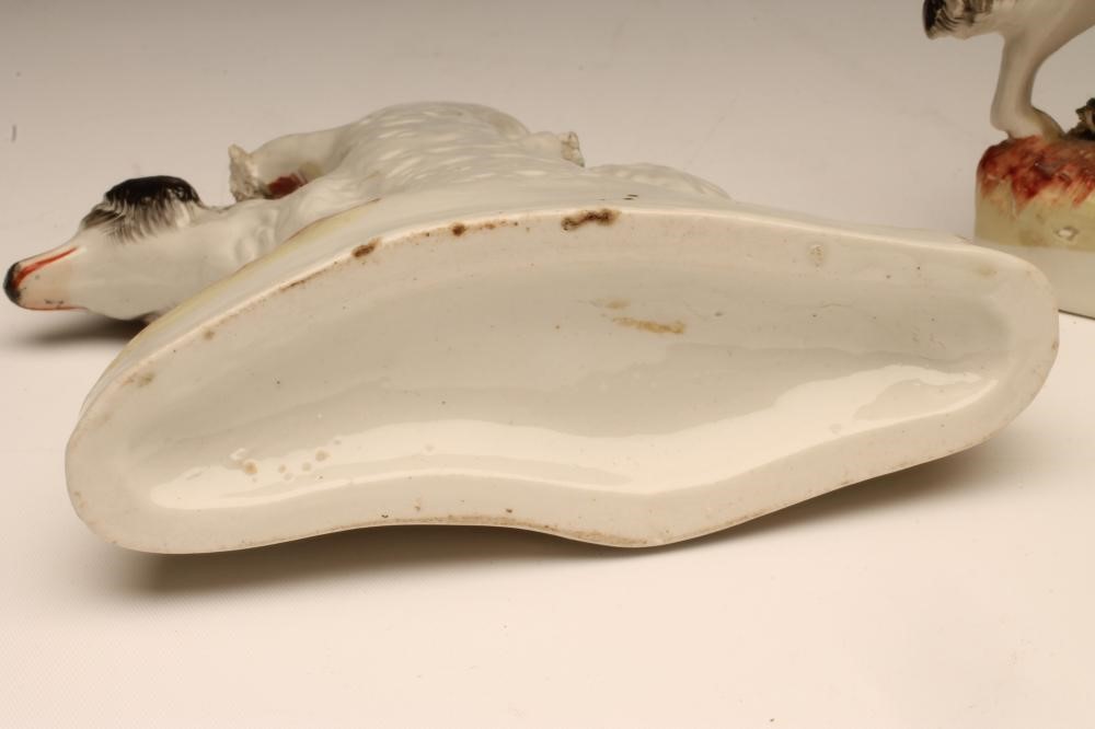 A PAIR OF VICTORIAN STAFFORDSHIRE POTTERY SPILL VASES as black and white retrievers standing against Image