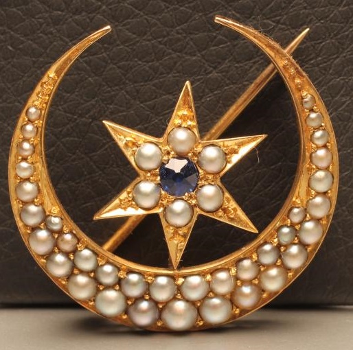 A VICTORIAN SEED PEARL CRESCENT BROOCH centred by a star gypsy set with a sapphire Image