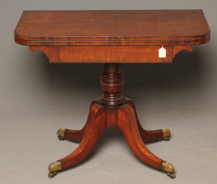 A REGENCY MAHOGANY FOLDING CARD TABLE of rounded oblong form with rosewood banding Image