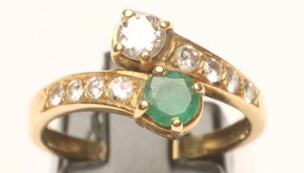 AN EMERALD AND DIAMOND CROSSOVER RING Image
