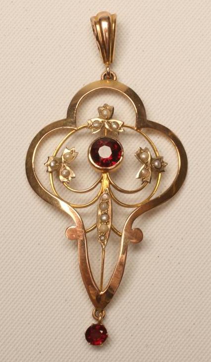 AN EDWARDIAN GARNET AND SEED PEARL PENDANT of oval quatrefoil form with wirework centre Image