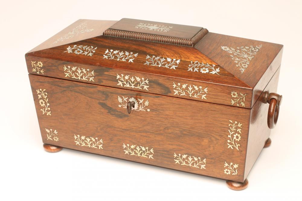 A REGENCY ROSEWOOD TEA CADDY of sarcophagus form with ring handles and raised upon four bun feet Image