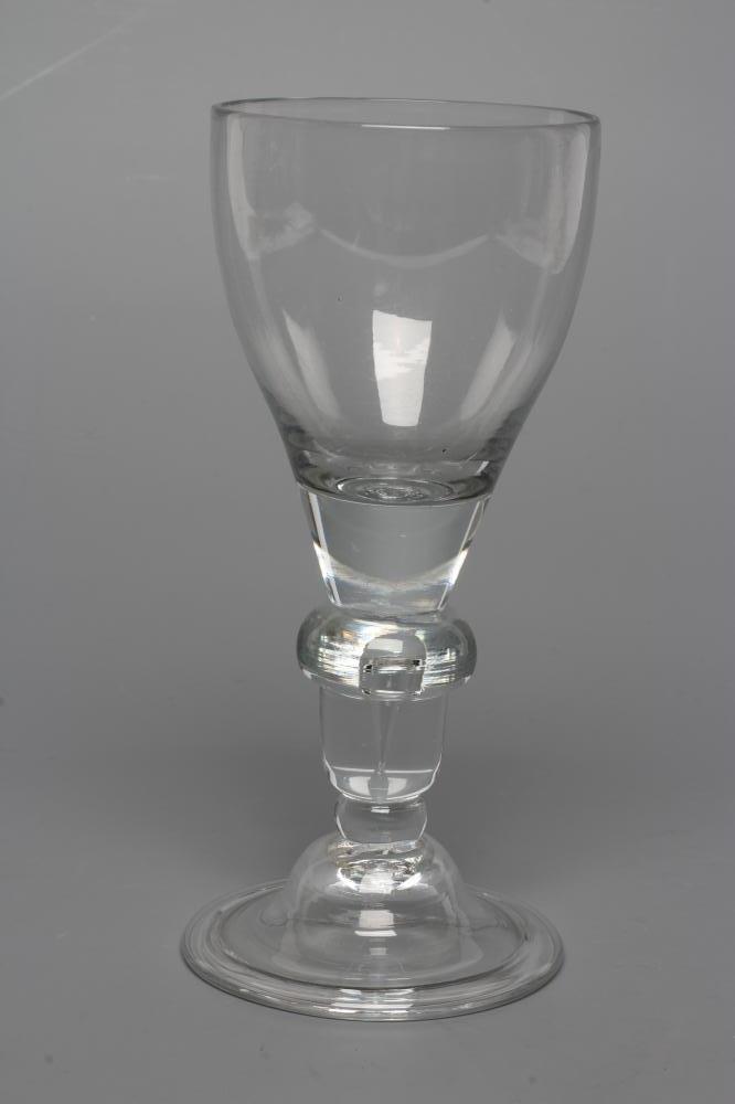 A GLASS GOBLET, early 18th century, the rounded funnel bowl issuing from an acorn knopped stem Image