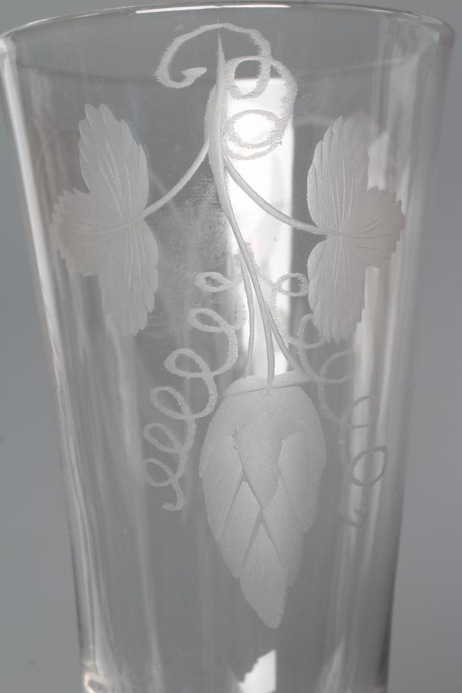 A GLASS ALE FLUTE, mid 18th century, the round funnel bowl engraved with hops and barley on a multi Image