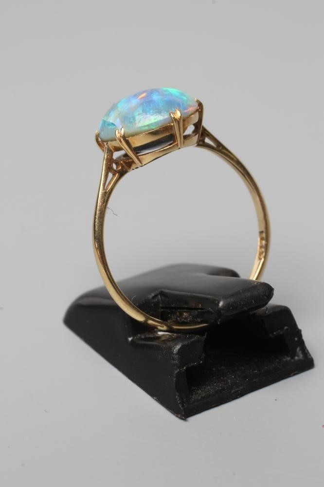 T. GAUNT - a black opal ring, the oval cabochon polished stone claw set to a plain shank, stamped Image
