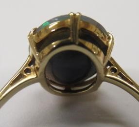 T. GAUNT - a black opal ring, the oval cabochon polished stone claw set to a plain shank, stamped Image