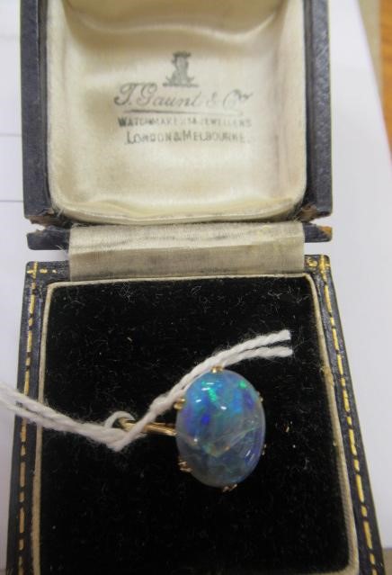 T. GAUNT - a black opal ring, the oval cabochon polished stone claw set to a plain shank, stamped Image