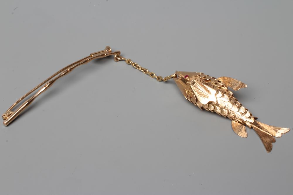 A NOVELTY FISHING BROOCH, the scaley articulated fish with ruby eyes, on a chain "line" and faux Image