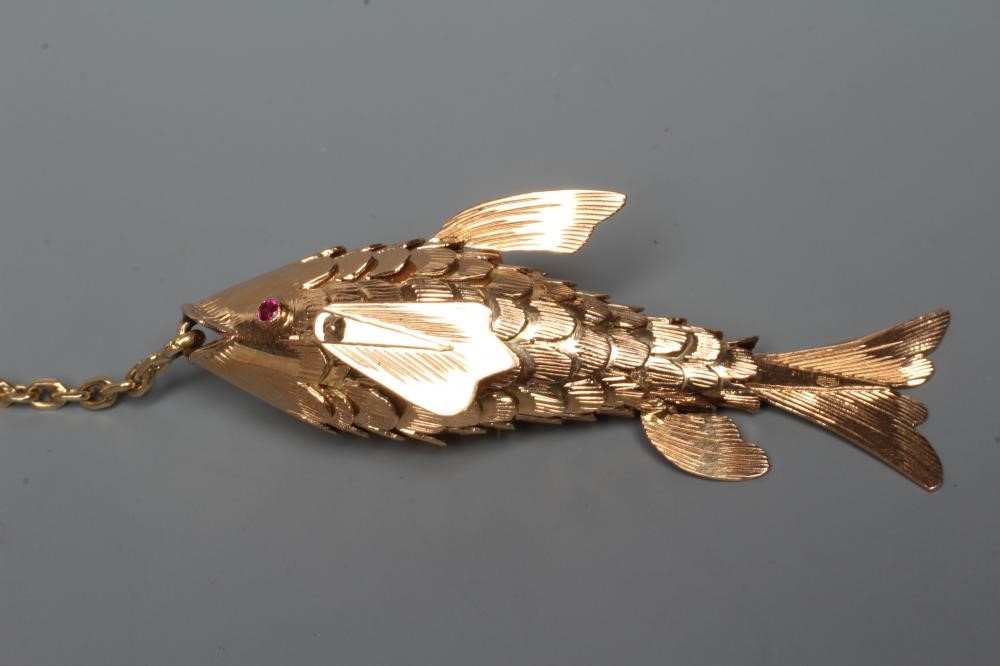 A NOVELTY FISHING BROOCH, the scaley articulated fish with ruby eyes, on a chain "line" and faux Image