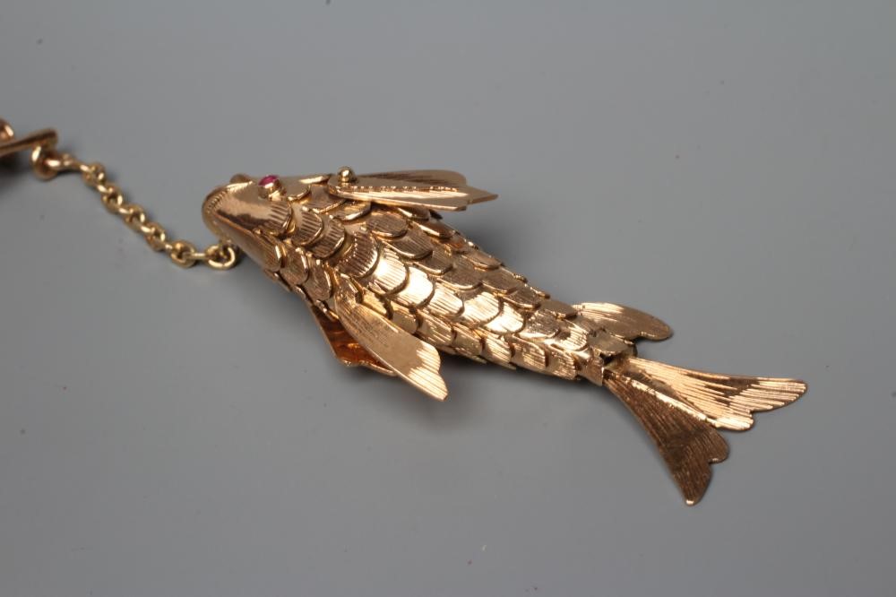 A NOVELTY FISHING BROOCH, the scaley articulated fish with ruby eyes, on a chain "line" and faux Image