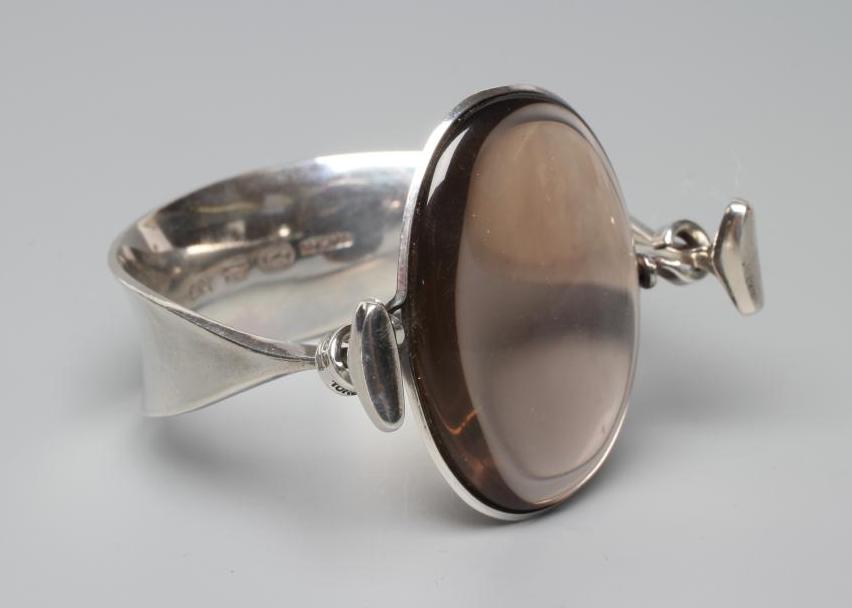 A GEORG JENSEN SILVER BANGLE designed by Vivianna Torun Bulow-Hube, the tension clamp centred by an Image