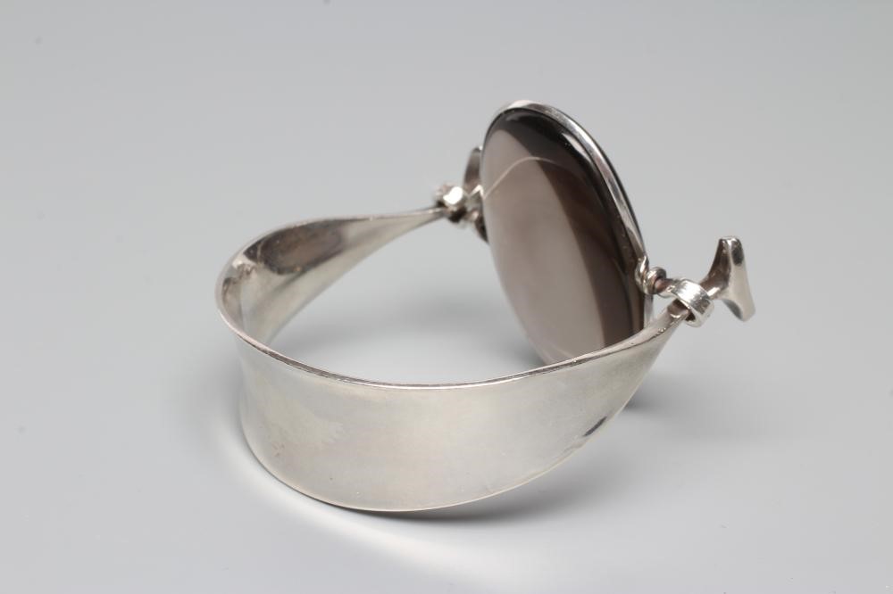 A GEORG JENSEN SILVER BANGLE designed by Vivianna Torun Bulow-Hube, the tension clamp centred by an Image