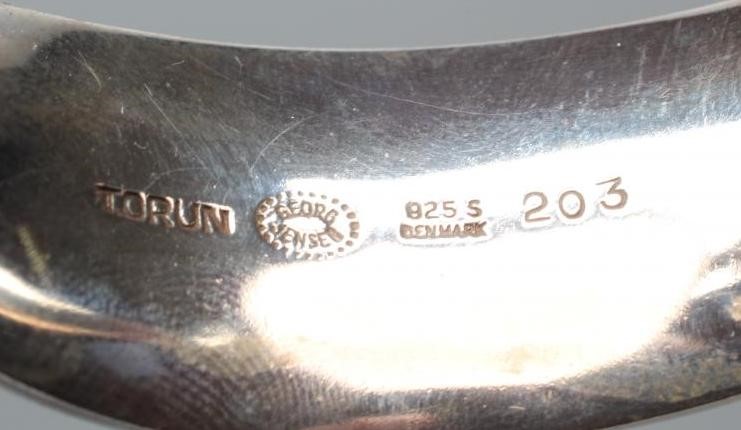 A GEORG JENSEN SILVER BANGLE designed by Vivianna Torun Bulow-Hube, the tension clamp centred by an Image