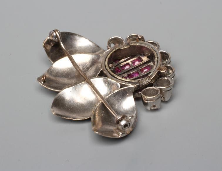 A MODERNIST RUBY AND DIAMOND FLOWER BROOCH, the five petals channel set with calibre cut rubies with Image