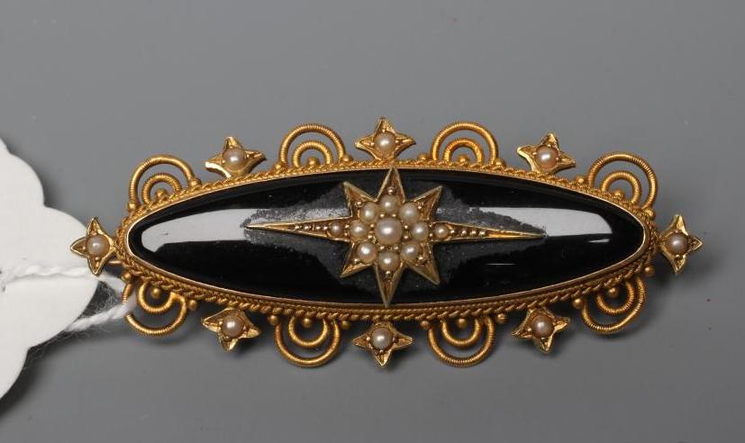 A VICTORIAN MOURNING BROOCH, the eliptical black panel centred by a gypsy set and seed pearl star, Image